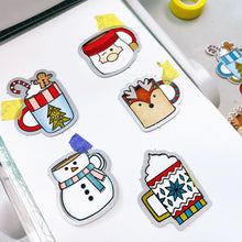 Load image into Gallery viewer, Catherine Pooler - Stamp &amp; Die Set - Holiday Mug. From the makers of the original Mug Shots Stamp Set comes Holiday Mug Shots Stamps and coordinating dies! Features all your favorite winter friends- Santa, Rudolf, Snowman and even the Gingerbread man. Available at Embellish Away located in Bowmanville Ontario Canada.
