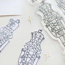 Cargar imagen en el visor de la galería, Catherine Pooler - Stamp &amp; Die Set - Nutcracker Sweet. Meet the cutest nutcrackers in town! This whimsical set features charming nutcrackers adorned in a delightful array of sweets and treats, including cupcakes, candy canes, and figgy pudding. Available at Embellish Away located in Bowmanville Ontario Canada.
