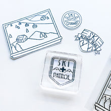 Load image into Gallery viewer, Catherine Pooler - Stamp &amp; Dies - Ski Lodge. The Ski Lodge Stamp Set gives you a view of the mountain along with badges and sentiments for adorable snowy card making! You can also add Alpine View Die for your wintery mix (Sold Separately). Available at Embellish Away located in Bowmanville Ontario Canada.

