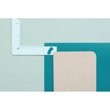 Cargar imagen en el visor de la galería, We R Memory - Book Cover Guide - Mint. Perfect book board placement, consistent gaps, trim corners at the proper angle, easily round corners and mark spot for elastic closure. It also includes a scan code for detailed instructions. Available at Embellish Away located in Bowmanville Ontario Canada.
